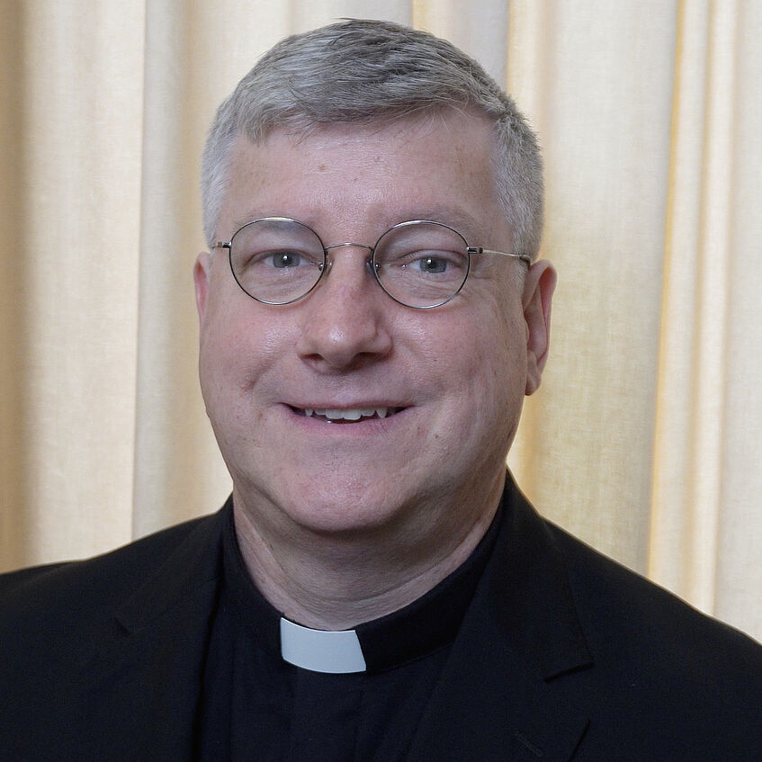 Portraitfoto eines Priesters in schwarzer Soutane