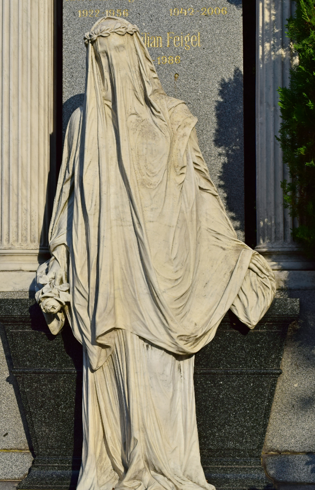 weiße, steinerne Statue vor einem Grabmal, Kopf von Schleier umhüllt